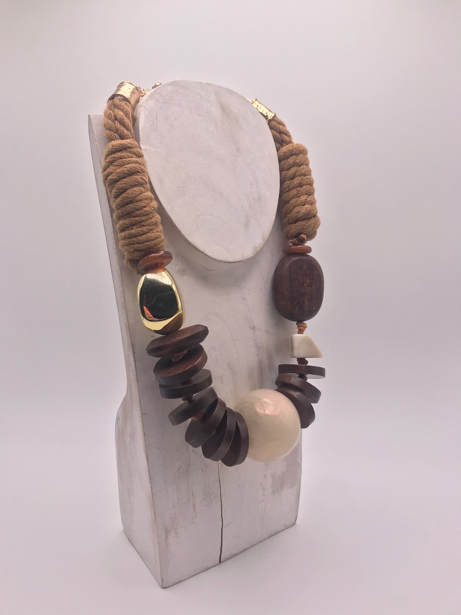 Colar artesanal de corda castanha e peças geométricas de madeira, bijuteria étnica boémia com esfera bege e detalhe dourado.