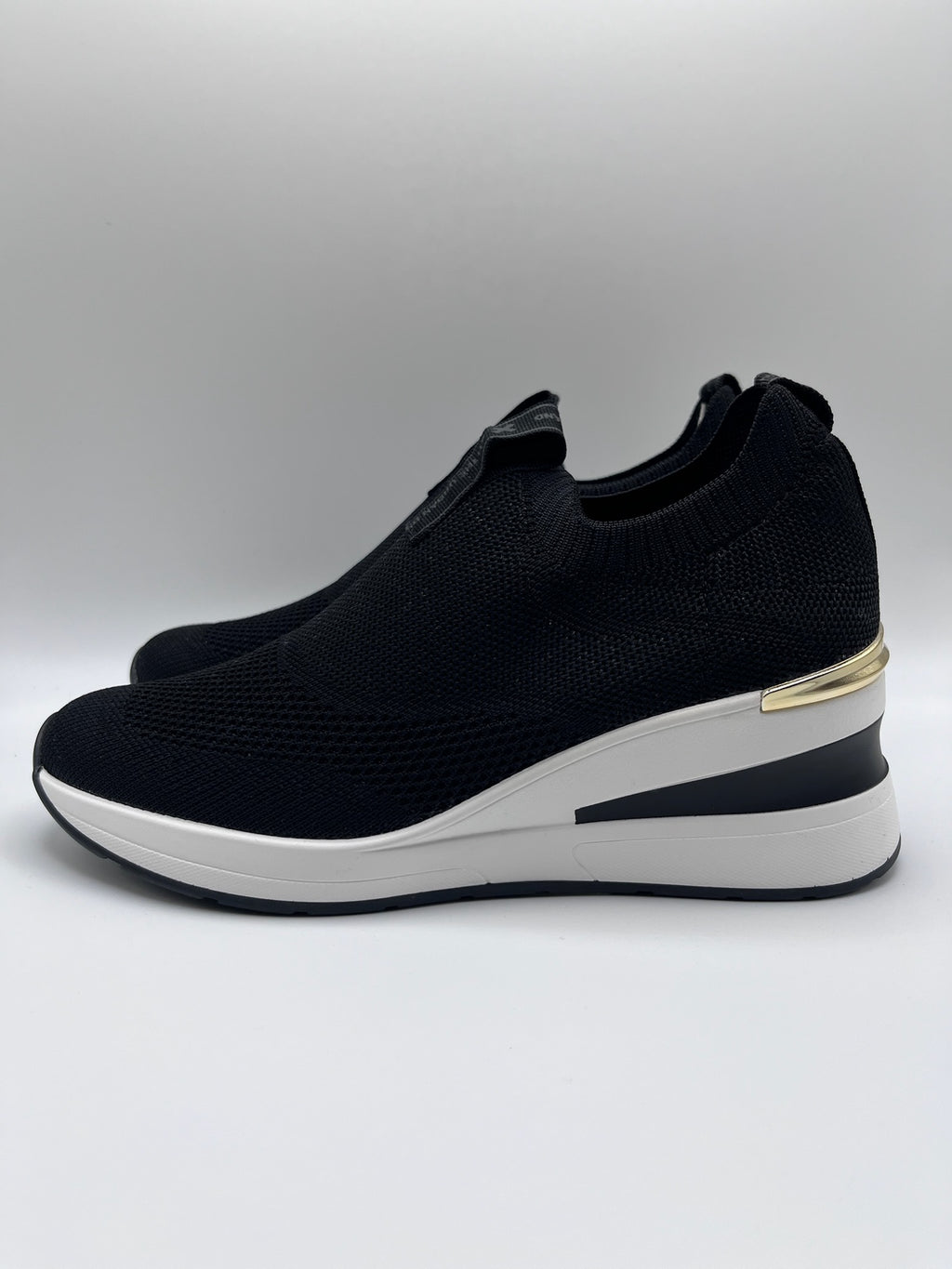 Sapatilhas Xti slip-on sem atacadores pretas com cunha e detalhe dourado; ténis de senhora em malha elástica confortáveis; calçado feminino moderno e leve para o dia a dia