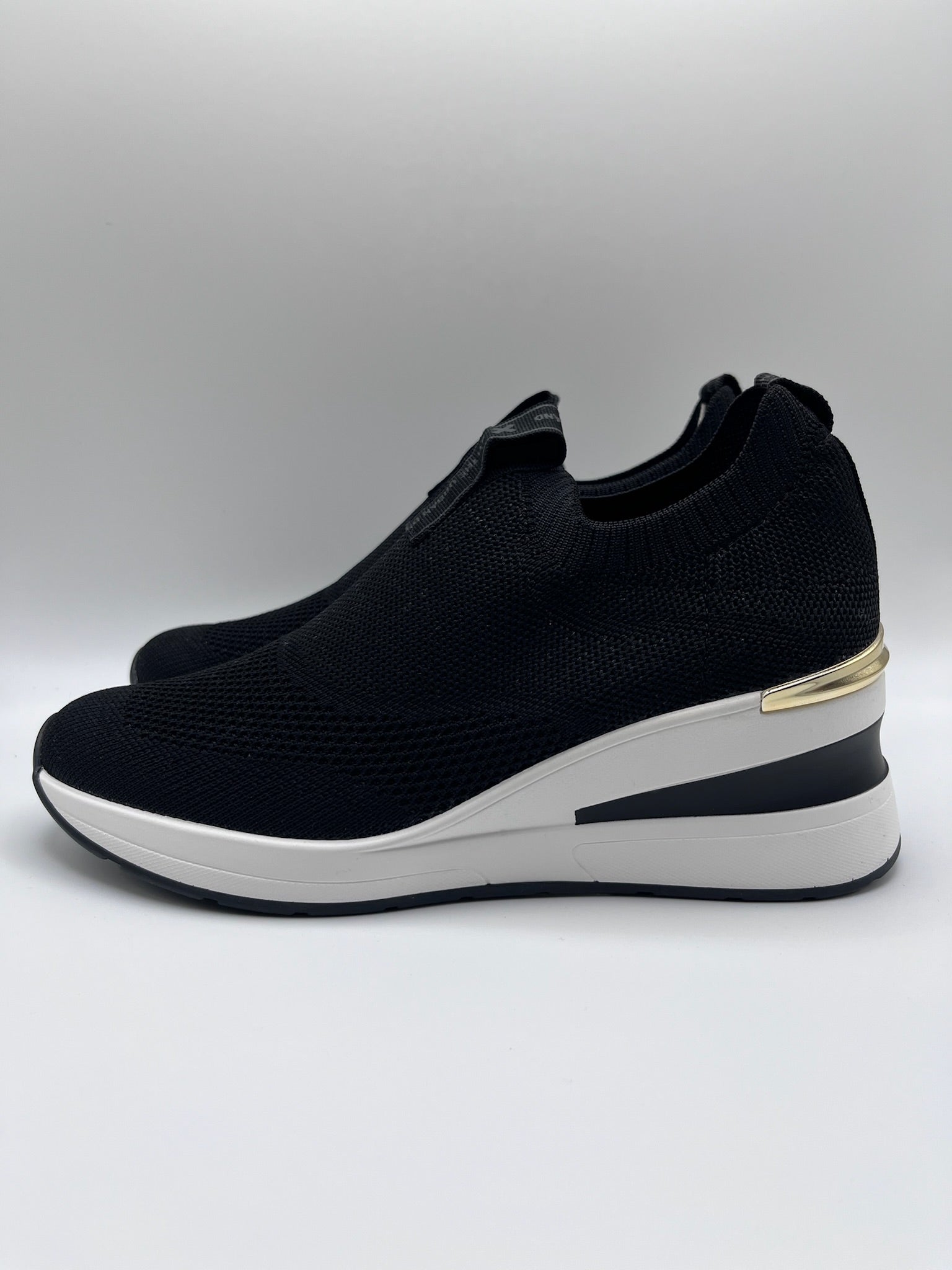 Sapatilhas Xti slip-on sem atacadores pretas com cunha e detalhe dourado; ténis de senhora em malha elástica confortáveis; calçado feminino moderno e leve para o dia a dia