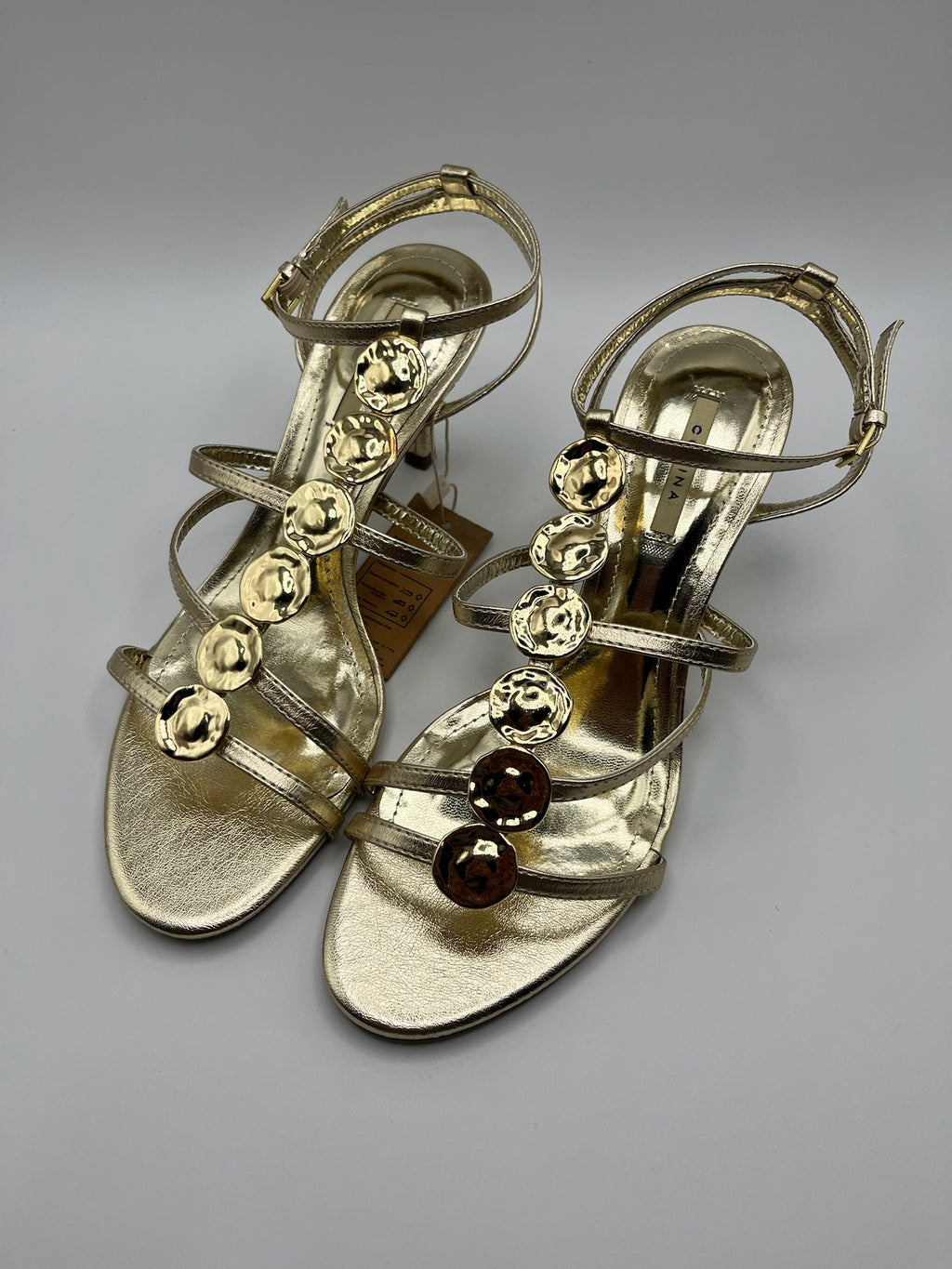 Sandália de Salto Alto Agulha Corina com Tiras Dourado Oro, Couro Sintético Metalizado, Detalhe Círculos de Metal, Festa Casamento Cerimónia Elegante Feminina