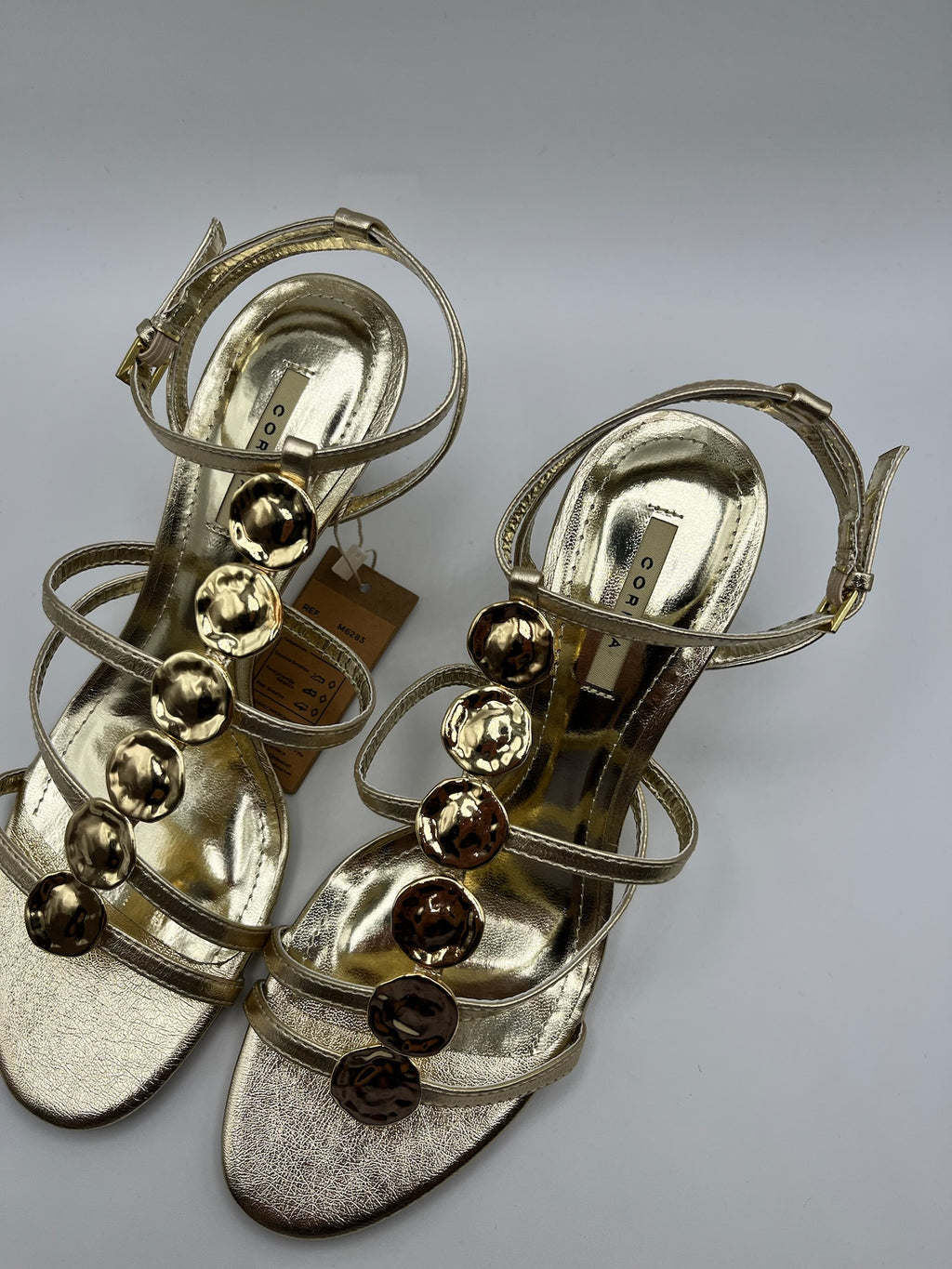 Sandália de Salto Alto Agulha Corina com Tiras Dourado Oro, Couro Sintético Metalizado, Detalhe Círculos de Metal, Festa Casamento Cerimónia Elegante Feminina